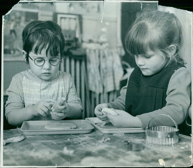 Rachel Roberts, 3, and Sarah Hornblow, 4, making pastry with their grandmother. - Vintage Photograph