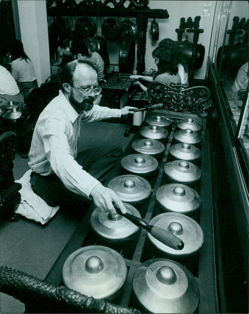 Musician John Pusey plays the bonangs at the Bate Collection of Musical Instruments. - Vintage Photograph