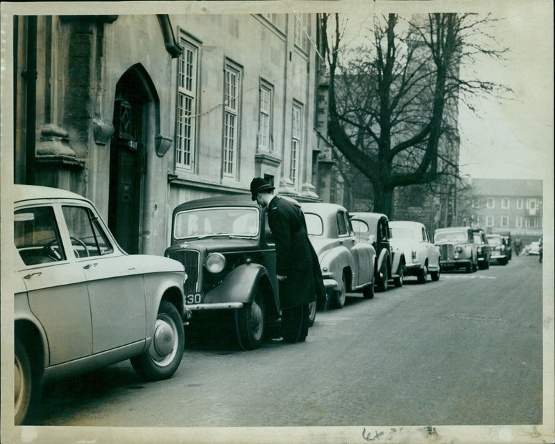 A man stands in a desolate street in front of a building with missing signs. - Vintage Photograph