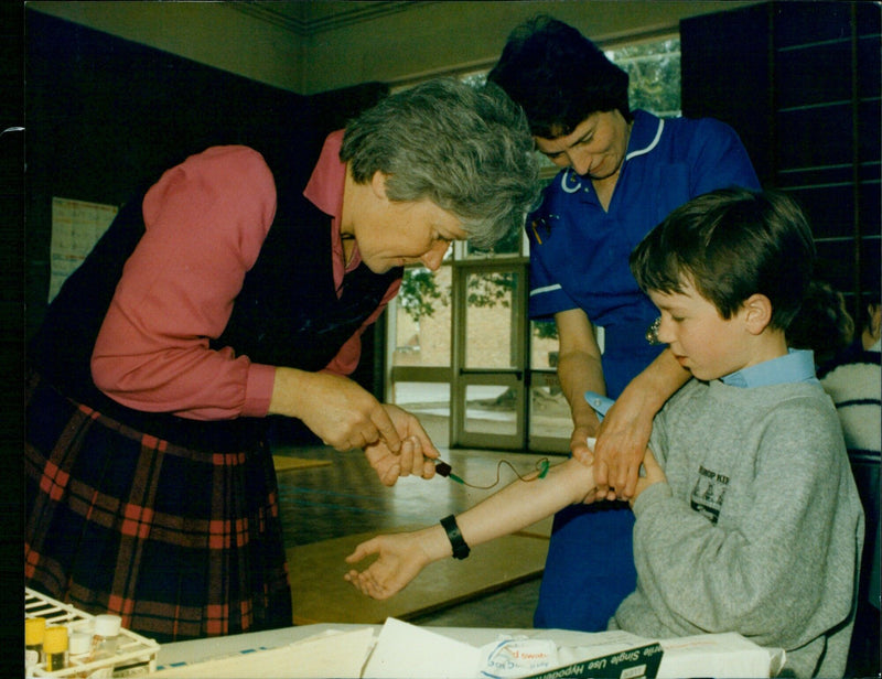 Mrs. Pay Sawter takes a blood sample from Frank Harrison (10) at Bishop Kirk School. - Vintage Photograph