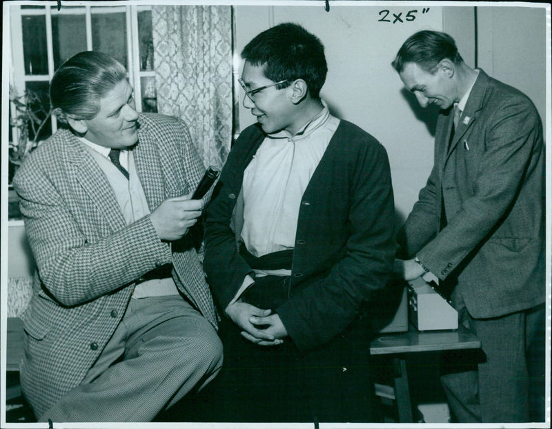 Craftsman Bill demonstrates the technique of stretching and squeezing tape to achieve a desired sound at a St. Community Music event. - Vintage Photograph