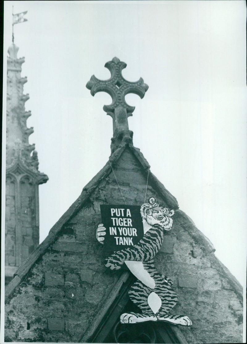 Students of Merton College, Oxford University, climb the college's chapel tower to install a "Put a Tiger in Your Tank" sign. - Vintage Photograph