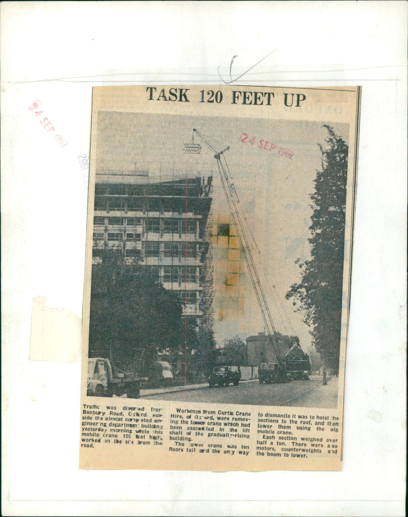 A mobile crane lifts sections of a tower crane from the roof of a construction site in Oxterd, England. - Vintage Photograph