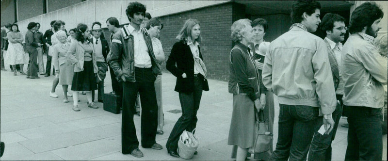 A group of people making a phone call from a public phone booth. - Vintage Photograph