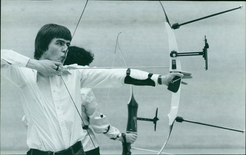 Archer Trevor Barker practices his aim in the University Gym. - Vintage Photograph