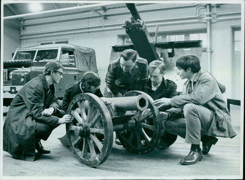 Sgt.-Major L. A. Curtis of the Royal Artillery Association shows a 100-year-old cannon to members of the production team of "Narrow Road to the Deep North." - Vintage Photograph