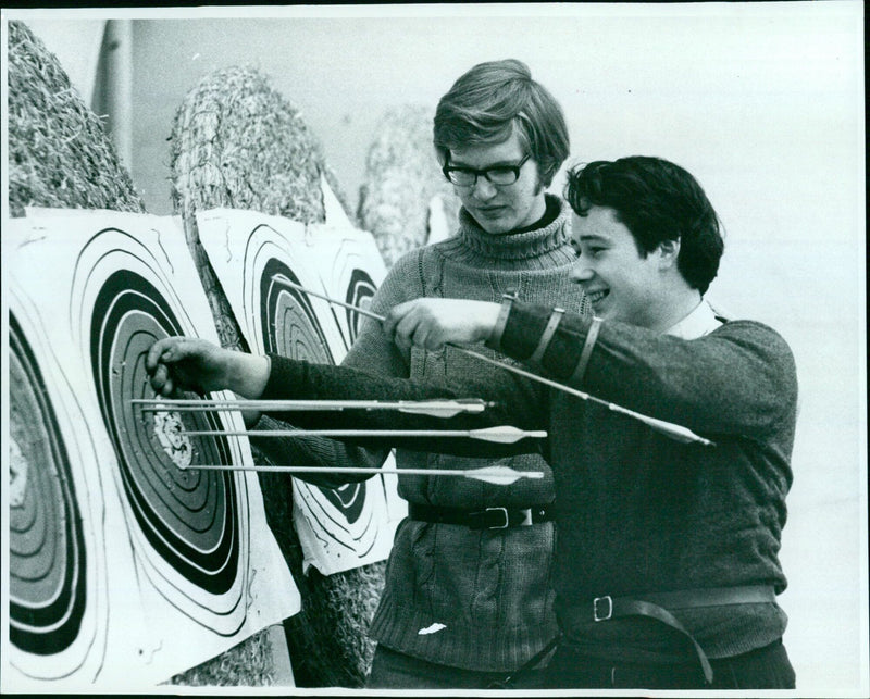 A male archer shooting an arrow at a target. - Vintage Photograph