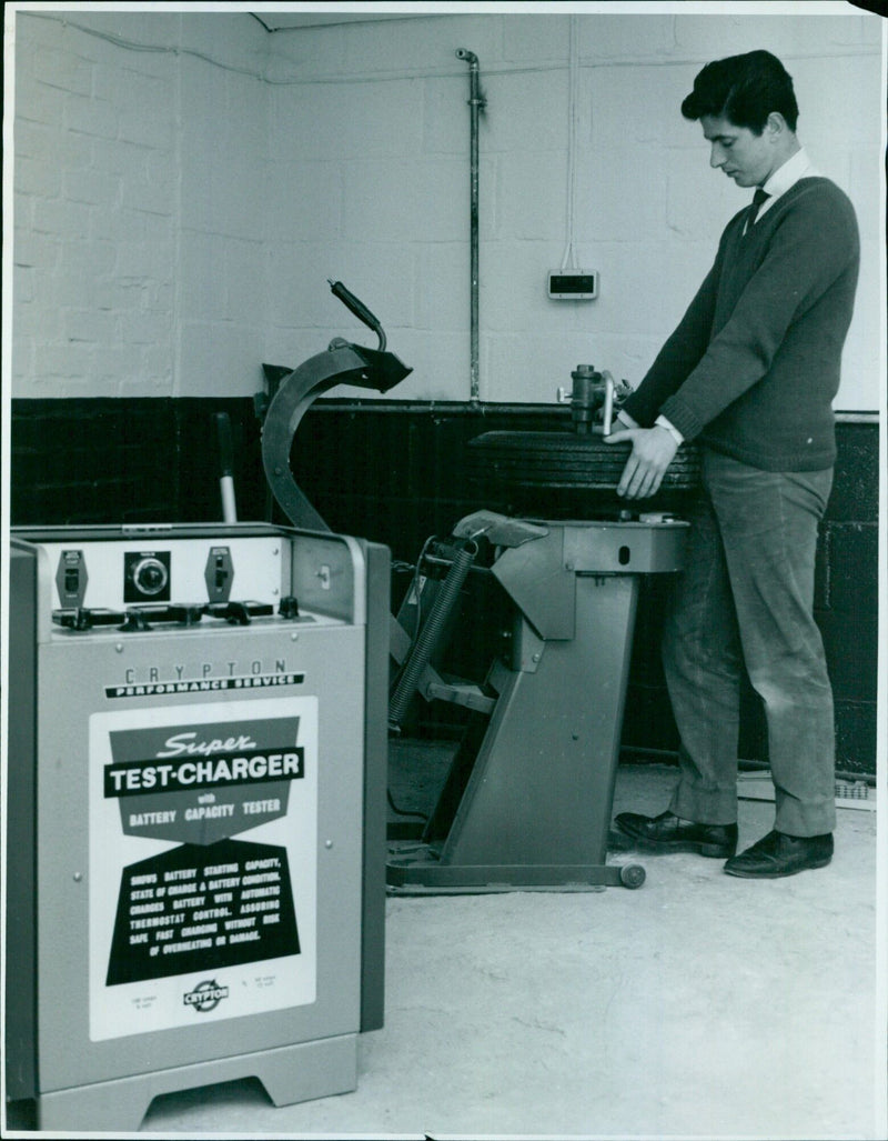 A technician demonstrates the features of a battery capacity tester. - Vintage Photograph