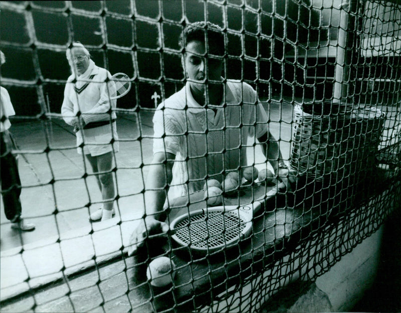 Merton College student Ludoker collects his tennis racket for a game. - Vintage Photograph