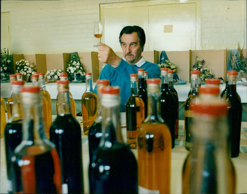 John Wrench of Thame judges the homemade wine entries at the Chinnor & District Flower and Produce Show. - Vintage Photograph