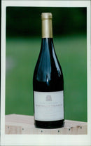 A bottle of Beaujolais Villages wine from the Cuvée à l'Ancienne label sits on a table. - Vintage Photograph