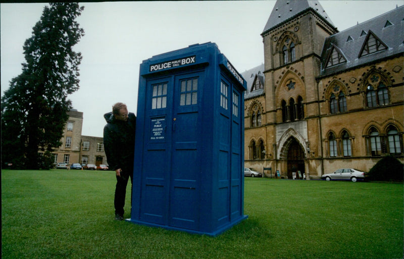 Anthony Wilson of New College inspects a police "pall box" on the lawn of the University Museum in Oxford. - Vintage Photograph