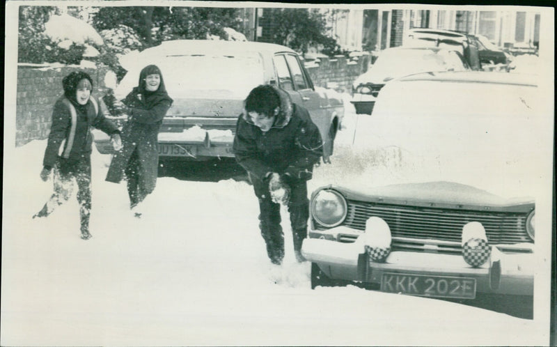 Friends enjoy a snowball fight in a wintery London street. - Vintage Photograph