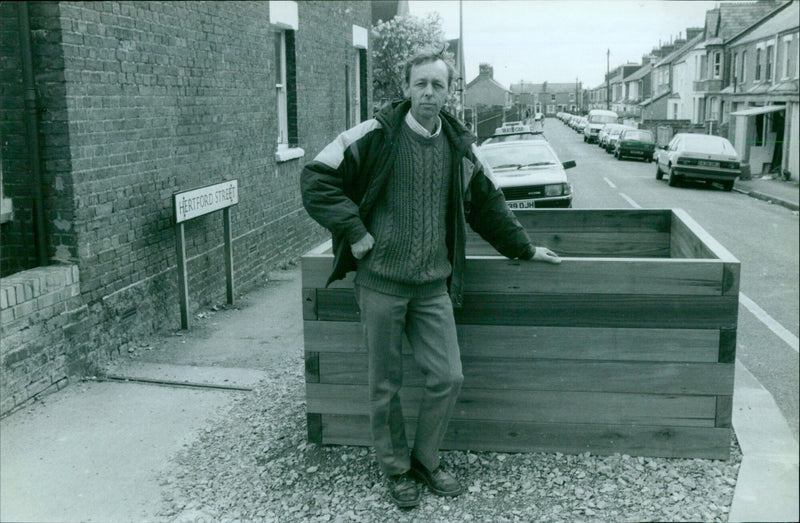 A taxi driver stands with his cab on Hertford Street in Oxford, England, next to a barrier set up by the city council. - Vintage Photograph