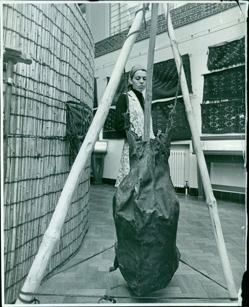 Mavis Roberts, an art student at Ruskin College, admires a butter container made from an animal skin and supported by three wooden poles at an Ashmolean exhibition. - Vintage Photograph