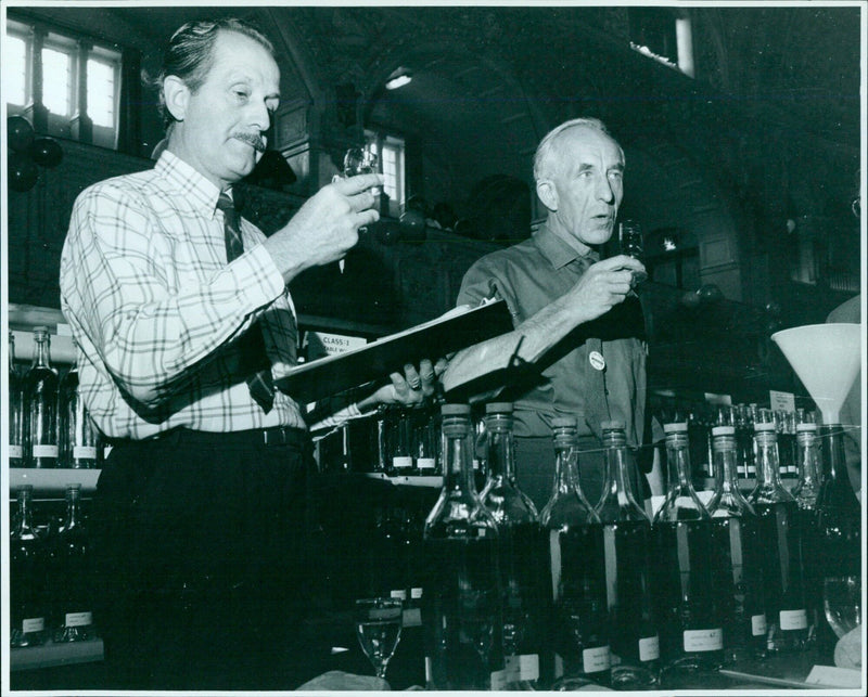 Two judges examine wines at the Wine Festival in Thame, England. - Vintage Photograph