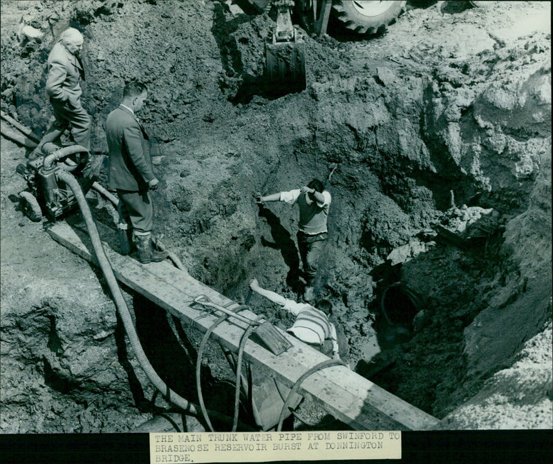 City Water Engineer Mr. H. H. Crawley inspects the damage caused by a main water pipe burst at Donnington Bridge. - Vintage Photograph