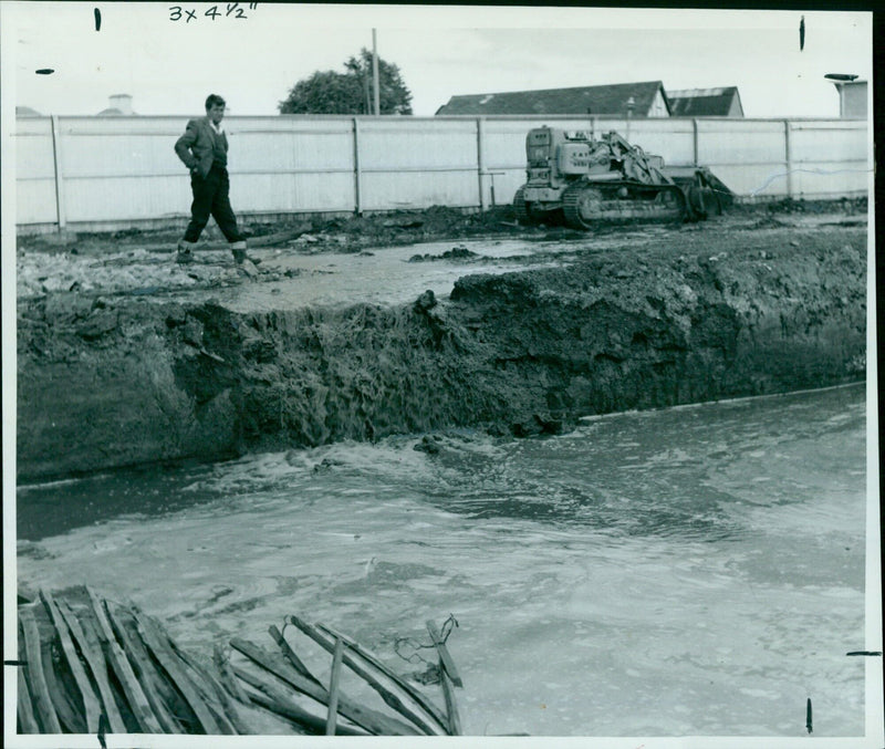 A woman using a metal detector to search for lost items in a grassy field. - Vintage Photograph