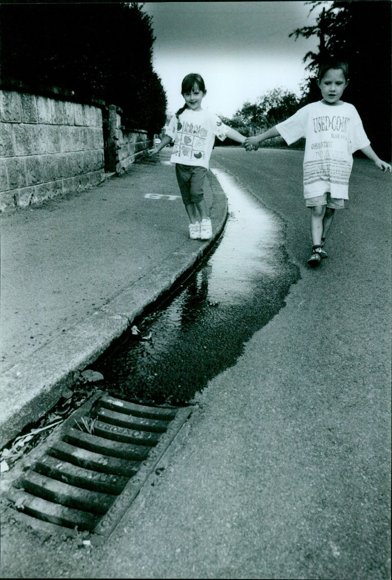 Jade and Daniel Clarke, aged 4 and 5, splash in a large puddle caused by a water leak in Lye Valley. - Vintage Photograph