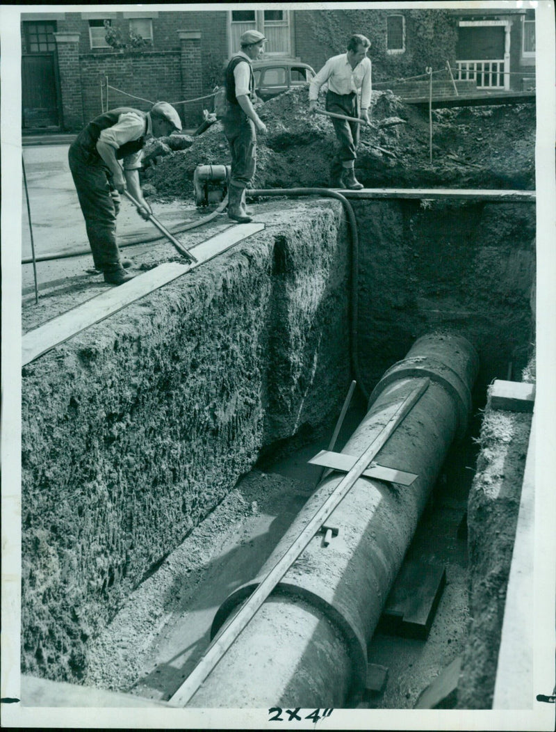 Workmen prepare to install a new valve in a water main lane. - Vintage Photograph