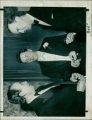 A man and woman standing in a field of sunflowers with the sun setting in the background. - Vintage Photograph