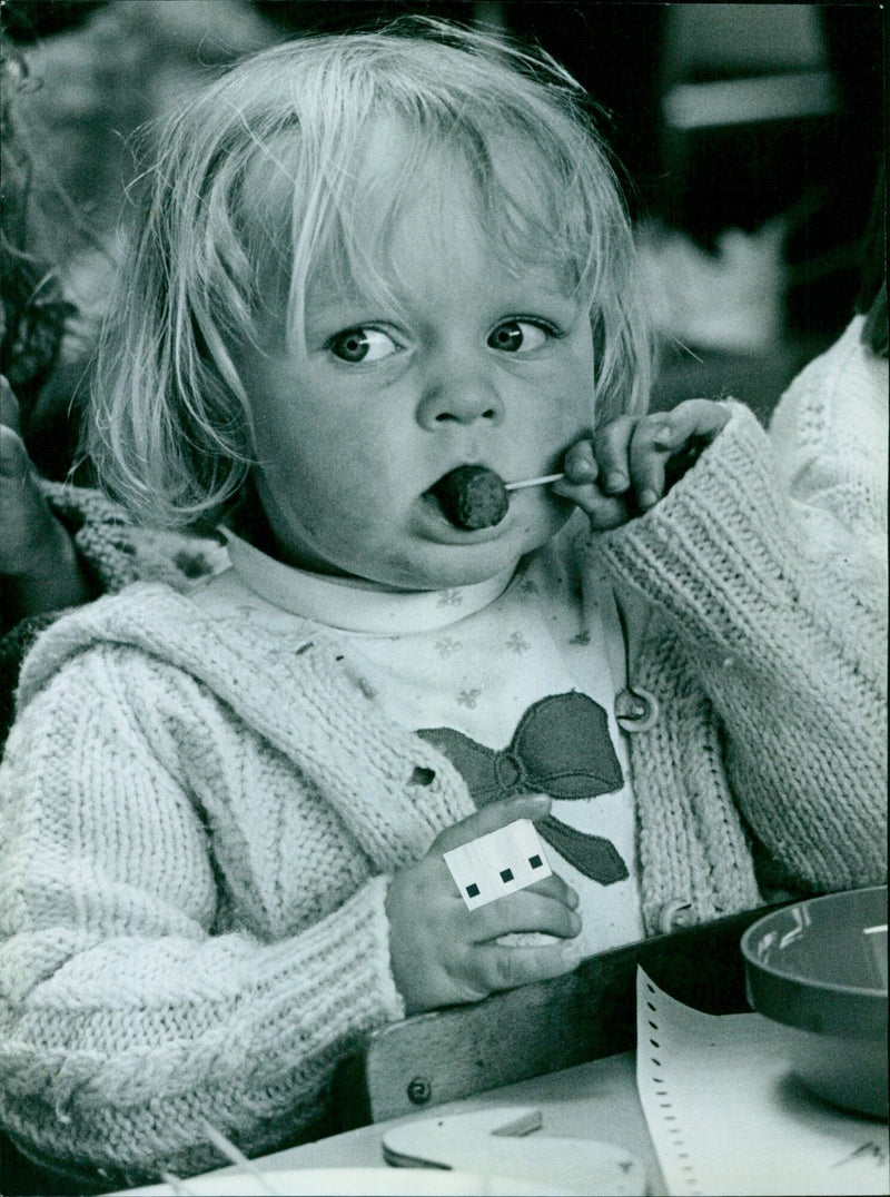 Heather Marriott, 2, celebrates the opening of the Polytechnic Nursery by having a sausage on-a-stick. - Vintage Photograph