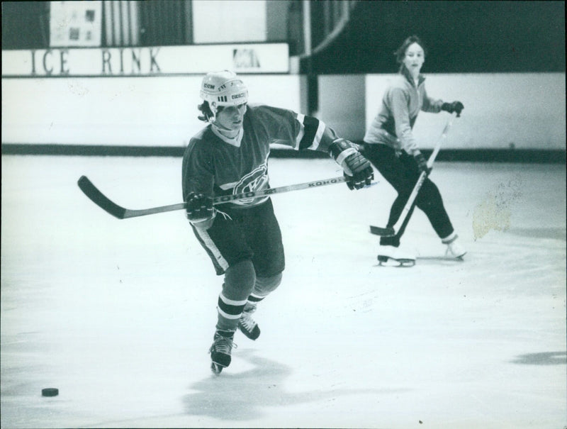 Skaters glide across the ice at an outdoor rink. - Vintage Photograph