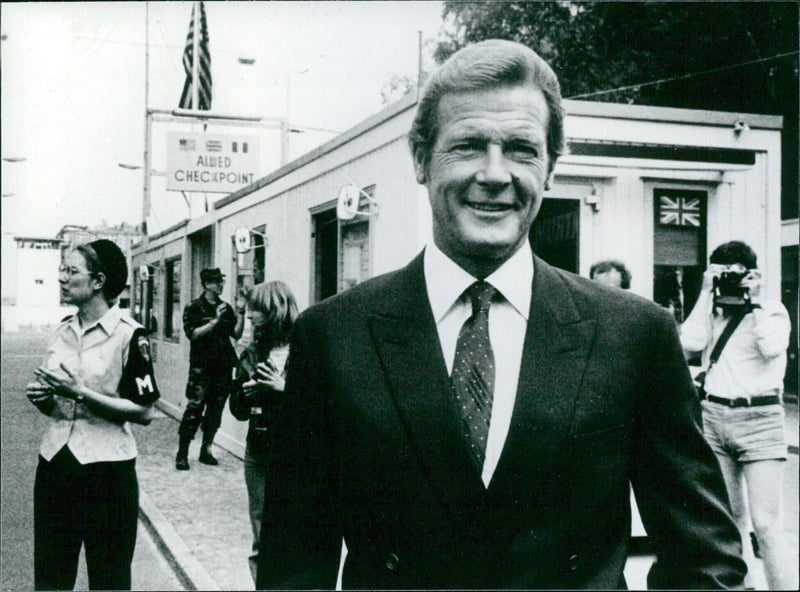 British actor Roger Moore, in character as James Bond, on location in Berlin at Checkpoint Charlie while filming the spy spoof "Octopussy". - Vintage Photograph