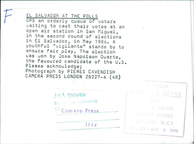 Voters in San Miguel, El Salvador line up to cast their ballots in the second round of elections in May 1984, supervised by a youthful "vigilante". - Vintage Photograph