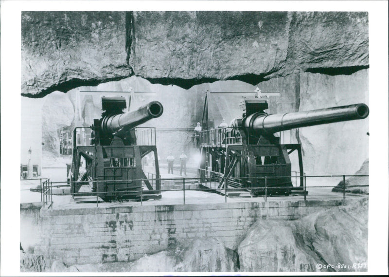 Members of the cast of "The Guns of Navarone" pose with replica cannons during filming. - Vintage Photograph