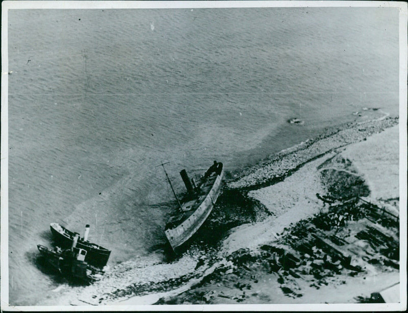 The wreckage of several British ships line the coast of the English Channel in September 1940, a stark reminder of the dangers of the conflict in Europe. Photo by KG Titische for Associated Press. - Vintage Photograph