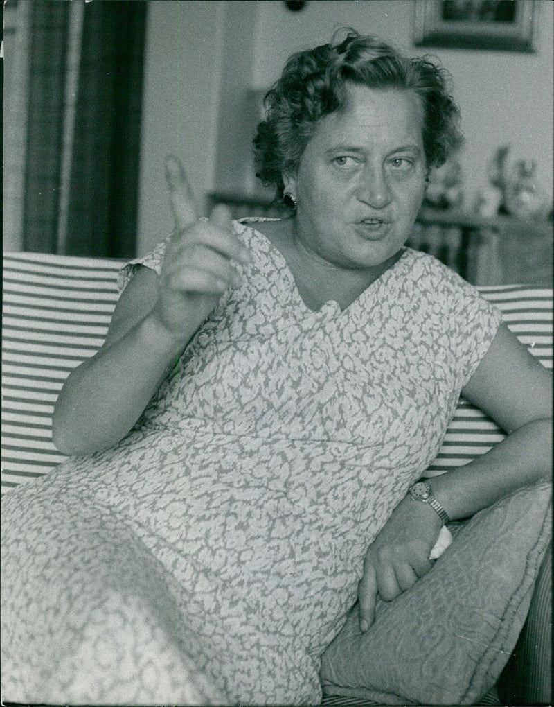 An elderly woman is seen standing in front of a house in Az 09708-29 Auder, Finland on August 30, 1957. - Vintage Photograph