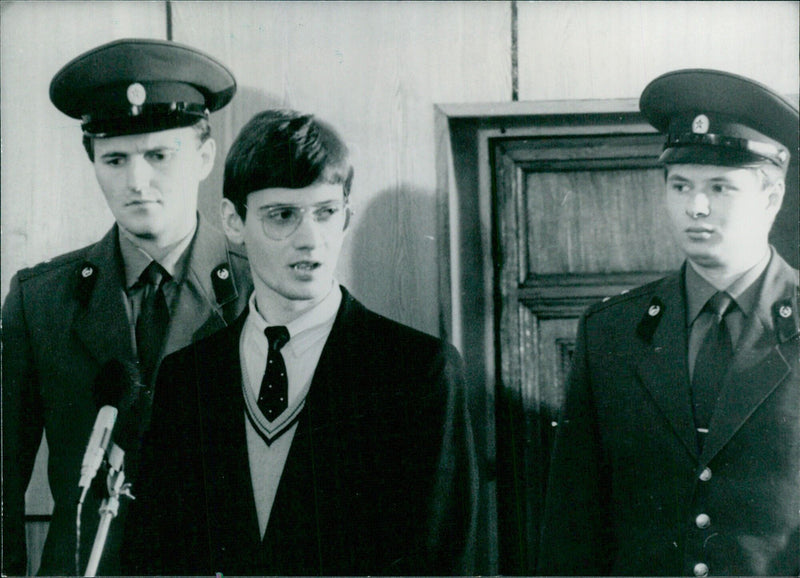 Mathias Rust, a 19-year-old West German flyer, is escorted by Russian guards in the Soviet Supreme Court after landing a Cessna in Red Square. Rust was sentenced to four years in a labour camp for the feat. - Vintage Photograph