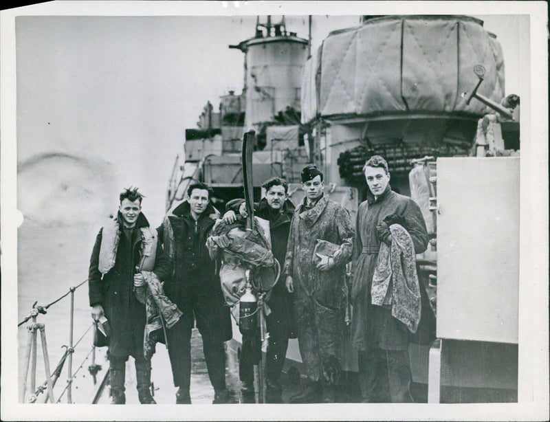 Five British airmen are seen on the deck of a destroyer after being rescued from the sea following a 24-hour period afloat on rubber floats. They had used up all their flares after a raid over enemy territory. - Vintage Photograph