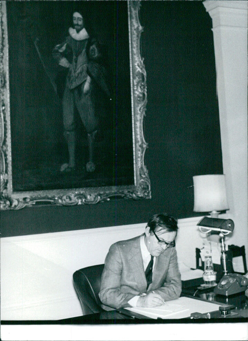 British Home Secretary Merlyn Rees at work in his Whitshall office, with a portrait of King Charles I in the background. - Vintage Photograph