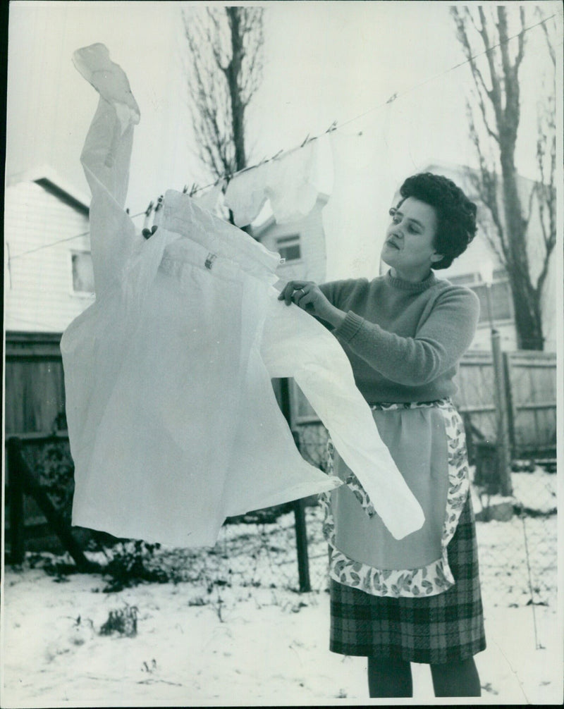 Anne Welham attempts to free her husband's frozen shirt from the line. - Vintage Photograph