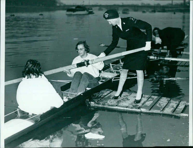 Red Cross official Mrs Rona Taylor gets a hand up with an oar at a 1971 event. - Vintage Photograph