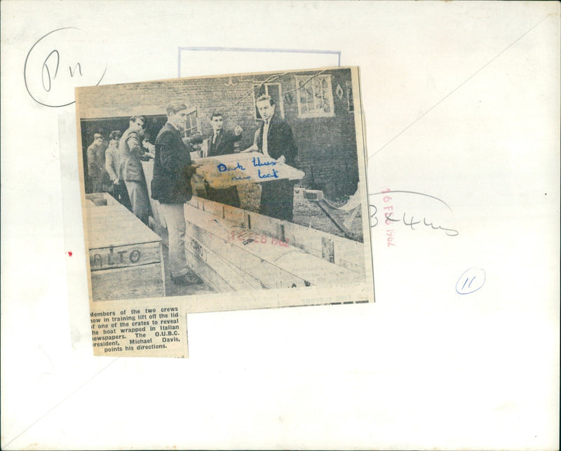 Members of the two crews in training reveal a boat wrapped in Italian newspapers. - Vintage Photograph