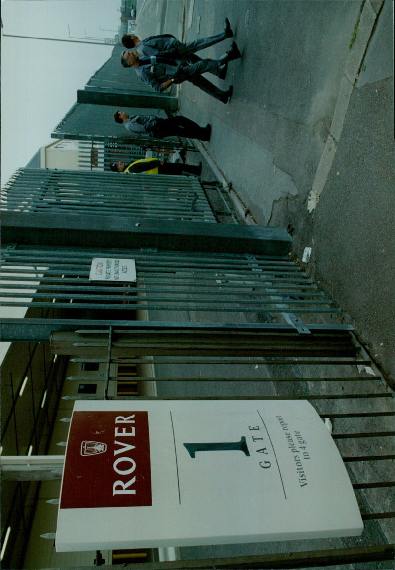 A security guard stands in front of a gate at a restricted access location. - Vintage Photograph