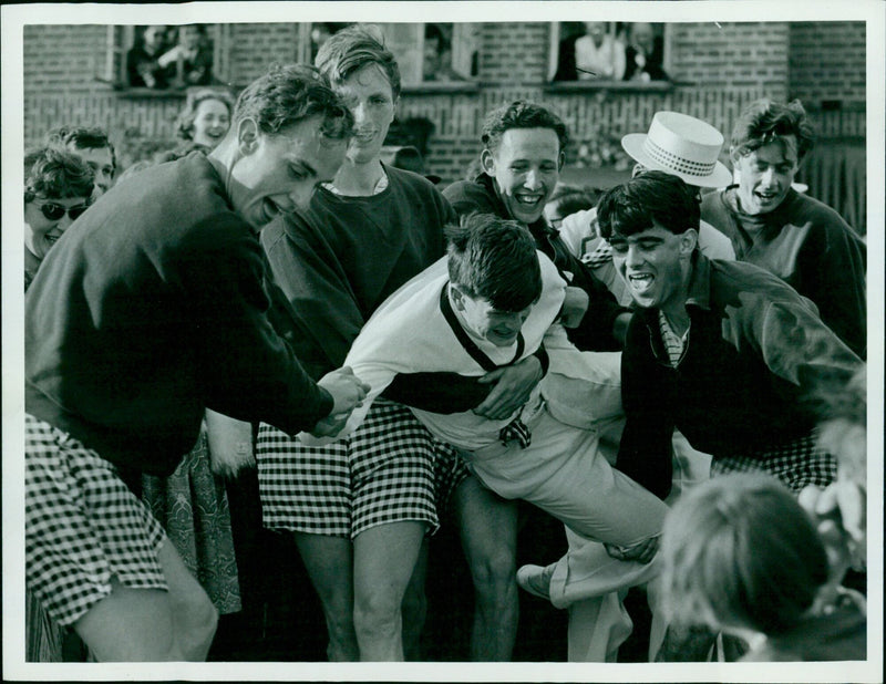 A rowing crew is cheered by a crowd as they make their way down the river. - Vintage Photograph