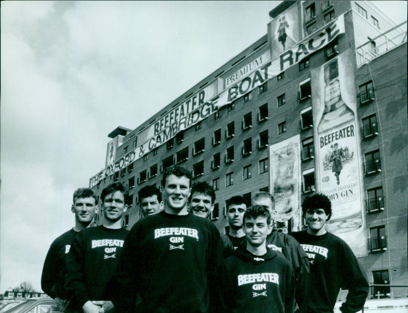 The Oxford crew watches the building of the world's largest Beefeater Gin advertising hoarding in London. - Vintage Photograph