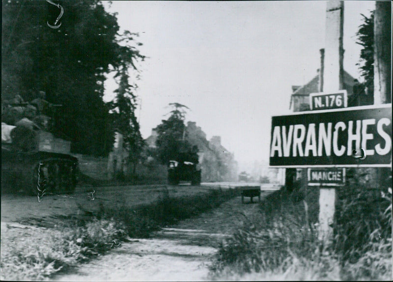 U.S. armored spearhead charges through Avranches, France, on July 31, 1944, marking a 38-mile advance of Lieutenant General Omar Bradley's First Army. - Vintage Photograph