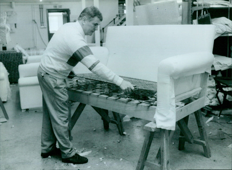 Rodney Carr adjusts a coil spring unit on a Keble two-seater settee. - Vintage Photograph