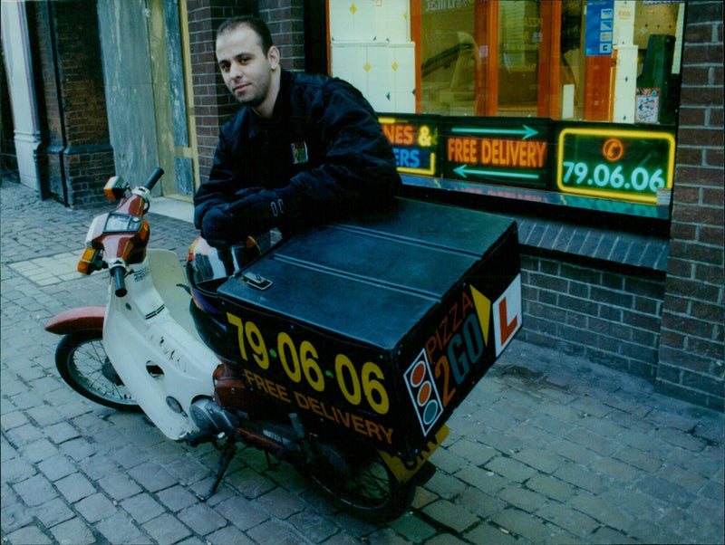 Deno receiving a delivery from "Pizza 2 Go" on a scooter. - Vintage Photograph