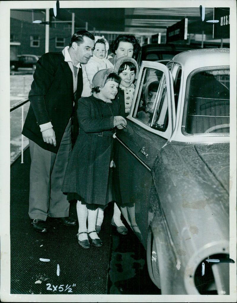 Mr. F. Hughes of Woodstock and his family viewing a Hillman bedie at the Pressed Steel works Exhibition in Cowley. - Vintage Photograph