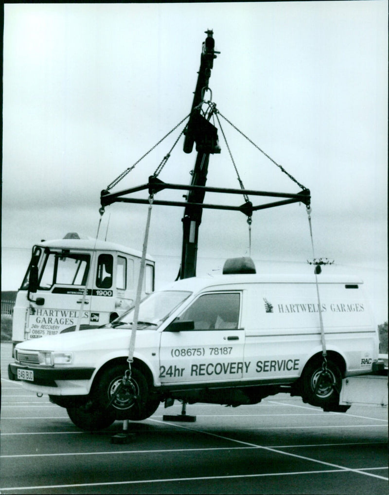 A Hartwells Garage 24-hour recovery service truck parked on the side of the road. - Vintage Photograph