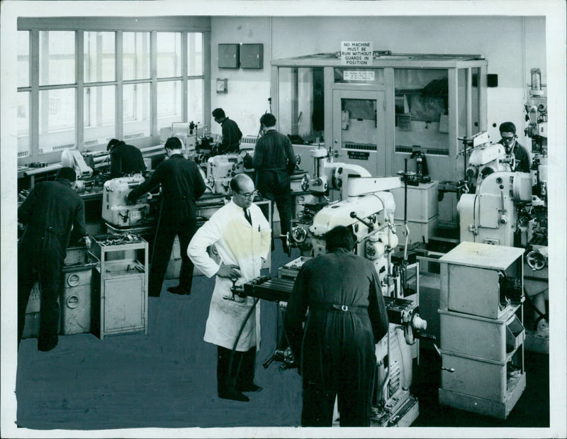 Factory workers operate machinery with guards in place to protect them. - Vintage Photograph