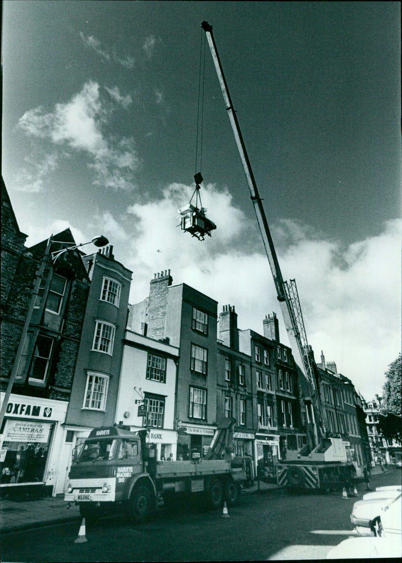 A printing machine is hoisted over shops in Broad Street, Bracknell. - Vintage Photograph