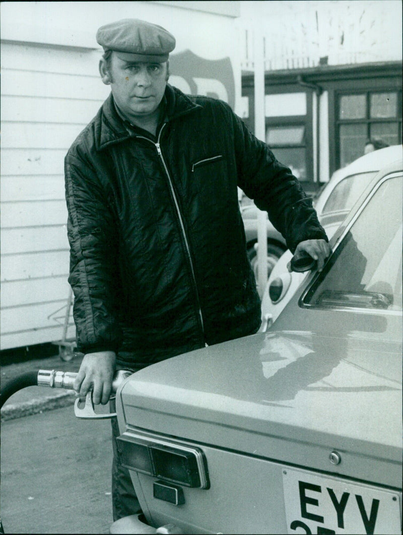 David Connor stands in a garage filled with car parts. - Vintage Photograph