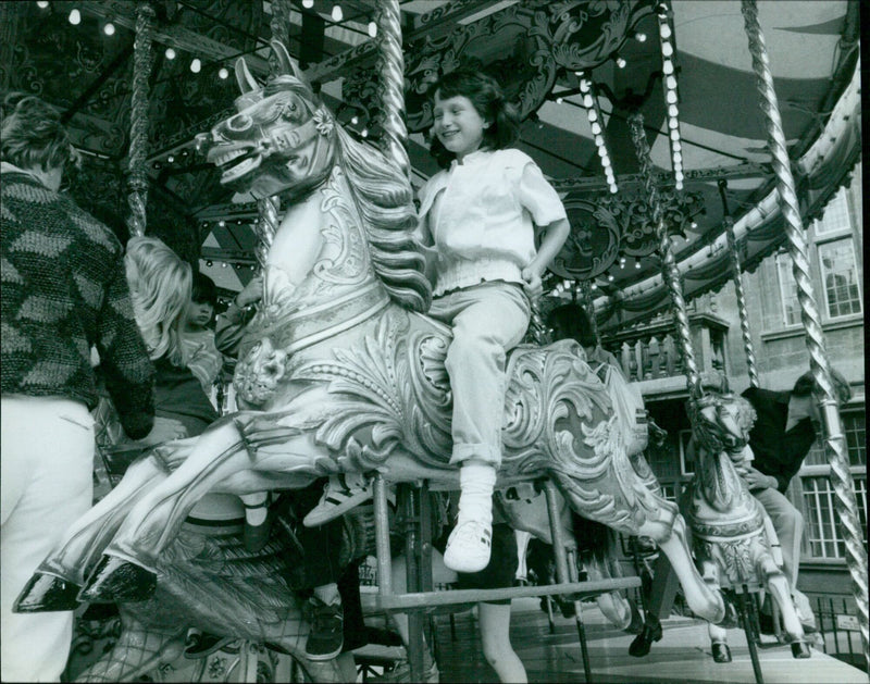 Joanna Hart enjoys a ride on the Galloping Horses. - Vintage Photograph